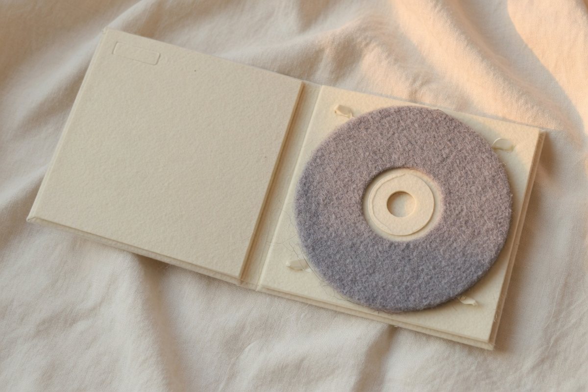 A felt CD in a plain cream case